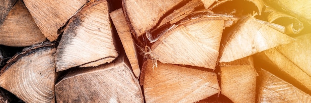 Photo textured firewood background of chopped wood for kindling and heating the house. a woodpile with stacked firewood. the texture of the birch tree. banner. flare