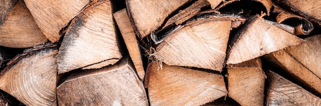 Photo textured firewood background of chopped wood for kindling and heating the house. a woodpile with stacked firewood. the texture of the birch tree. banner