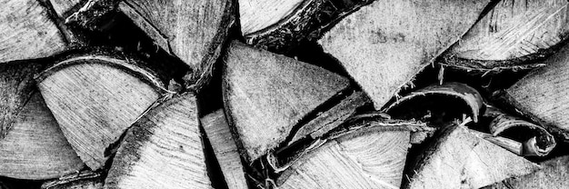 家を燃やし、暖房するための刻んだ木のテクスチャード薪の背景。薪を積み上げたウッドパイル。白樺の木の質感。ブラックホワイトまたはグレーの色調。バナー