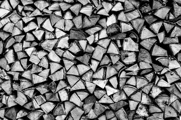 Textured firewood background of chopped wood for kindling and heating the house. a woodpile with stacked firewood. the texture of the birch tree. toned in black white or gray color