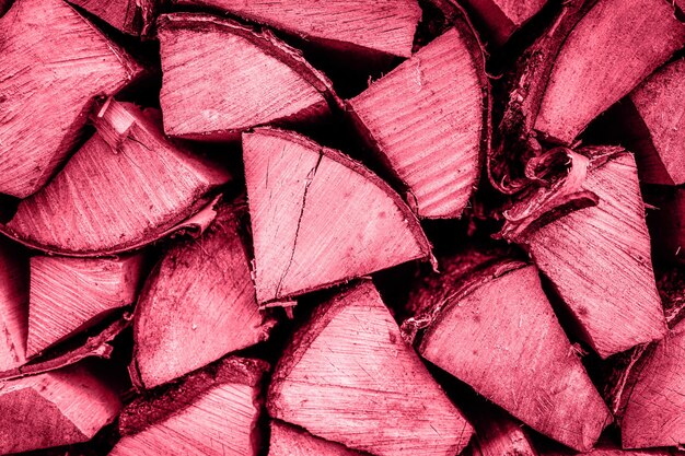 Textured firewood background of chopped wood for kindling and heating the house a woodpile with stacked firewood the texture of the birch tree toned in viva magenta trend color of the year 2023