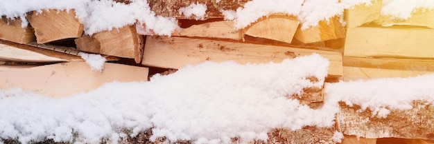 Textured firewood background chopped wood for kindling woodpile stacked firewood birch tree covered fresh icy frozen snow and snowflakes cold weather and snowy winter time season banner flare