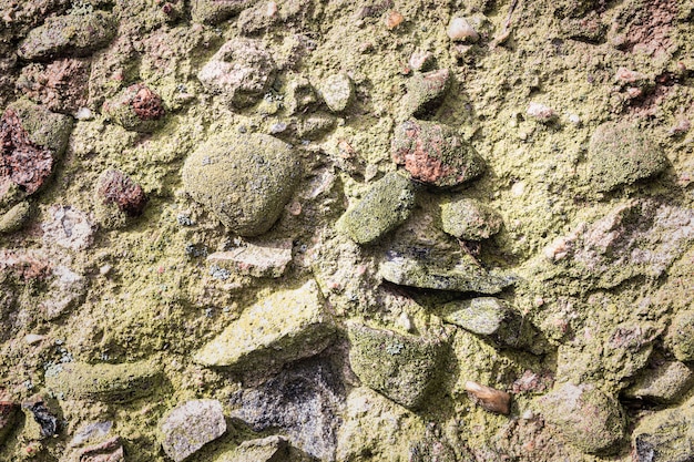 Textured old granite stone wall of large gray mossy stones as background.