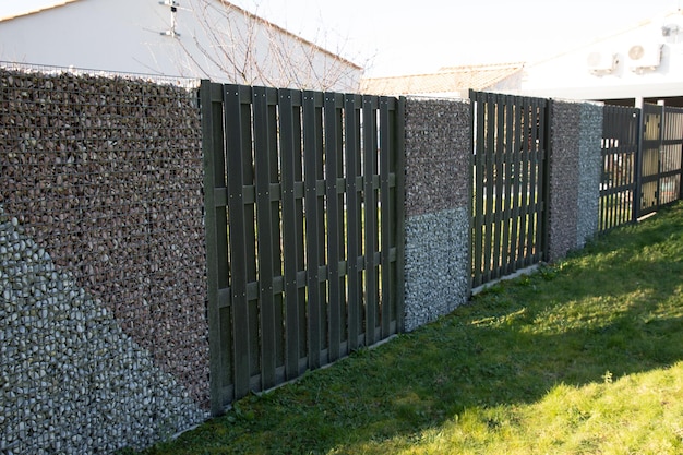 Textured residential house fence made of mesh and stones of gabion wall filled with stones