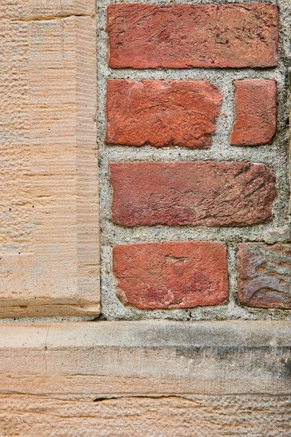 Textured tan colored concrete wall with rectangular red brick section background asset