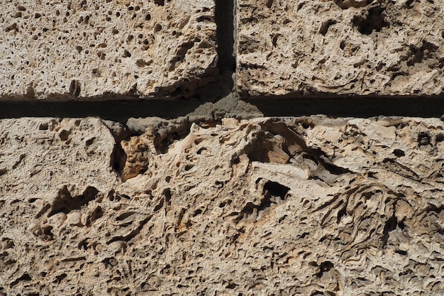 Textured wall lined with beige shell rock tiles Closeup of a wall made of ancient shell rock Holes irregularities of natural building material Church wall in Banja Koviljaca Serbia