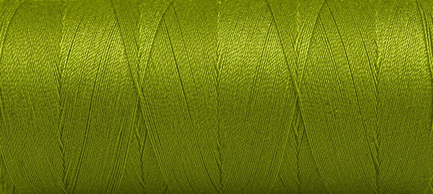 Textuur van draden in een spoel van groene kleur op een witte achtergrond