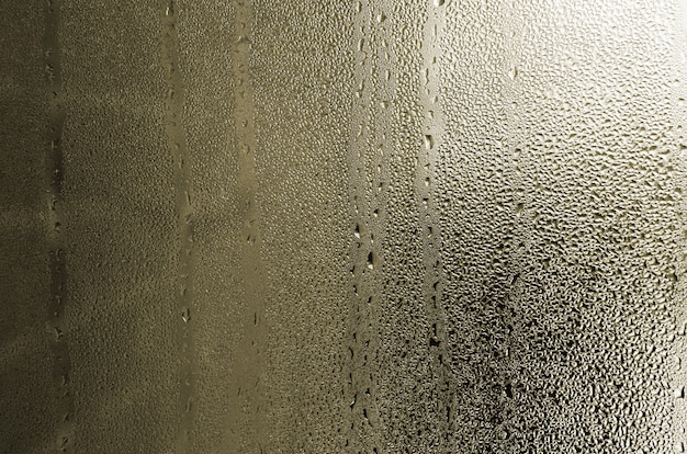 Textuur van een druppel regen op een glas natte transparante achtergrond. Afgezwakt in gele kleur