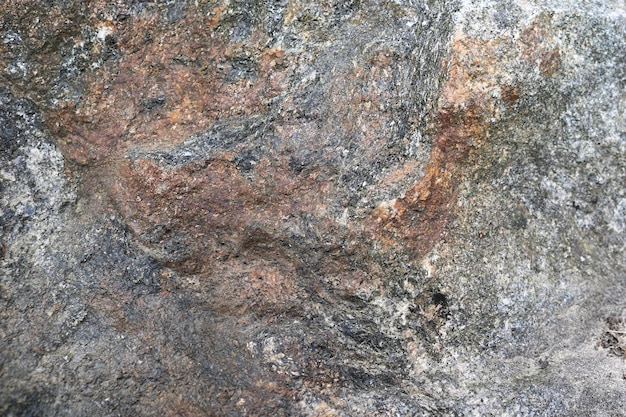 Textuur van een grijsbruine veelkleurige oude massieve steen met scheuren, hobbels en patronenachtergrond