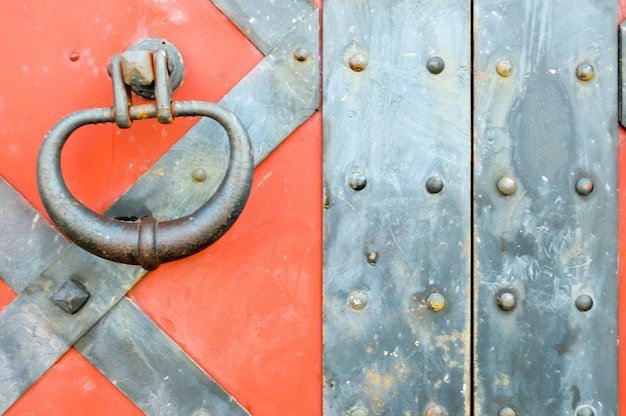 Textuur van een oude oude middeleeuwse rode antieke stevige ijzeren metalen deur met klinknagels en spijkerpatronen