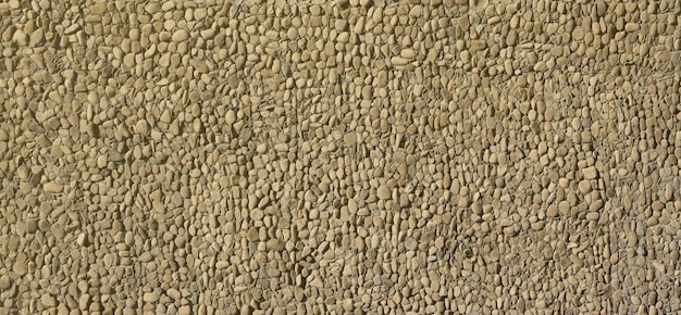 Textuur van een stenen muur met kleine ronde kiezelstenen die deel uitmaken van een steenmuur als achtergrond of