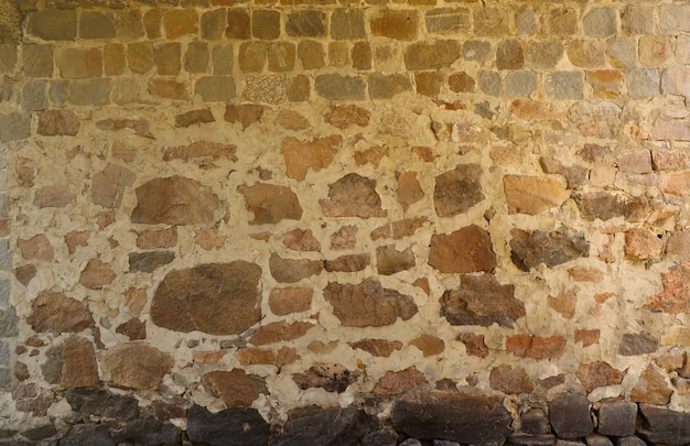 Foto textuur van een stenen muur met veel grote bruine en grijze stenen bewapend met cement oude kasteel steen