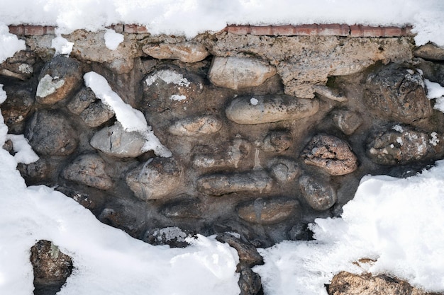 Textuur van geplaveide stenen in betonnen oude muur in de winter met sneeuw