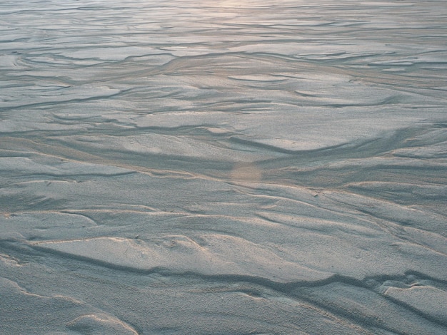 Textuur van wit zand in de stralen van de dageraad natuurlijke achtergrond Bovenaanzicht van het zandstrand close-up kopie ruimte