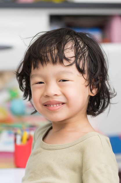 ぼかしの背景に緑のシャツとタイのアジアの少年の笑顔