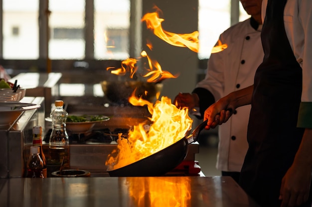 Тайский мужчина профессиональный шеф-повар готовит еду с огнем на кухне ресторан кулинарный класс кулинарная школа кулинарные уроки в кулинарной школе