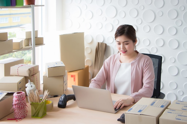 A Thai Asian woman is sitting on a laptop printing document in a working room