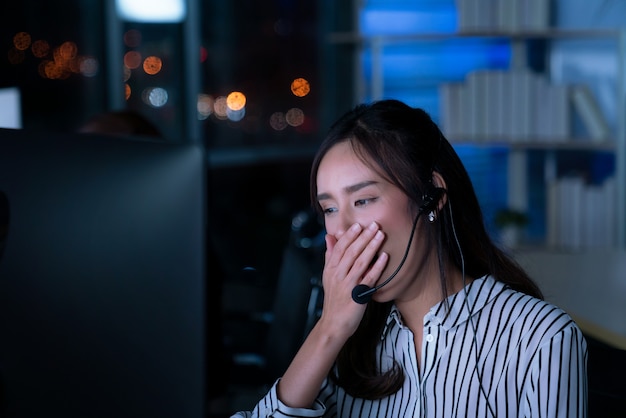 Thai asian women call center business people get headache and migraine from working late night shift for helping assistance customer in workplace at night time