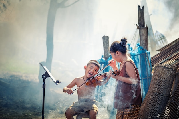 Photo thai boy and rural girls playing violin at her home garden.