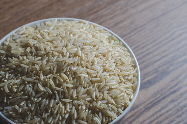 Thai brown jasmine rice close up in white bowl on wood table background