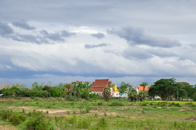 Thai Buddhist Temple at rural countryside in Thailand cloudy rainy season landscape.