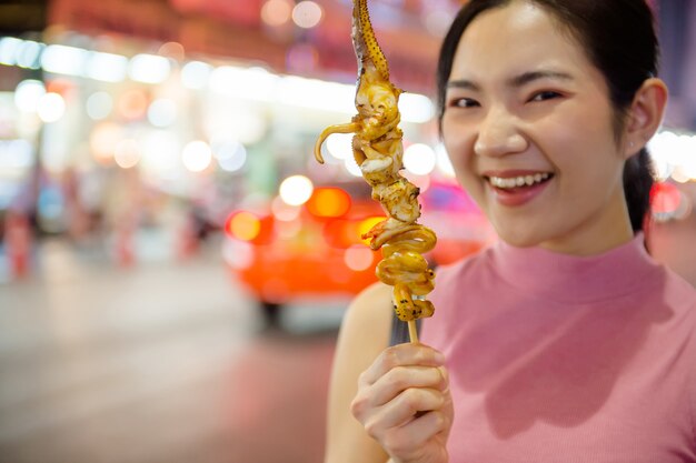 タイと中国の観光客がバンコクのチャイナタウンのヤワラー通りを散歩して屋台の食べ物を試食