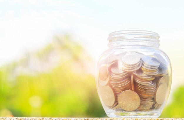 Thai coins in glass bottles on natural bokeh background.