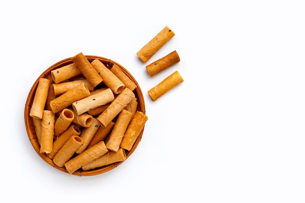 Thai crispy coconut rolls in bamboo basket on white background.