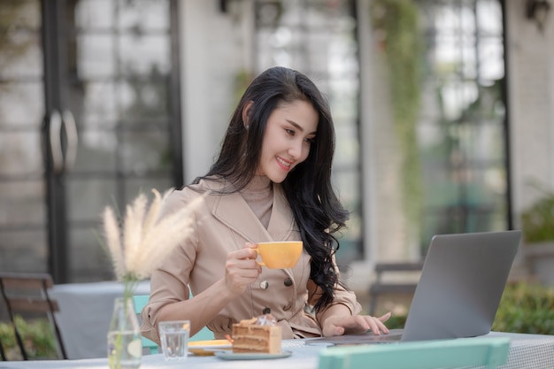 Thai designers businessmen sitting drinking coffee and cake while holding  working on laptop via wi-fi internet  