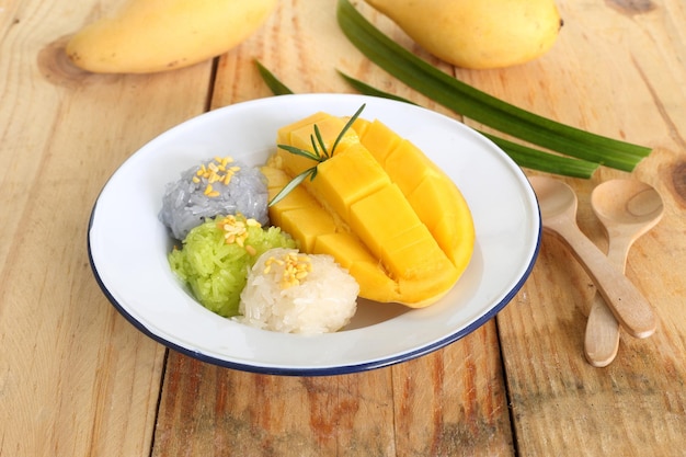 Foto piatto del primo piano del dessert delizioso famoso tailandese del mango maturo fresco dolce con tre colori di riso appiccicoso verde dal pandan e porpora dal fiore del pisello di farfalla