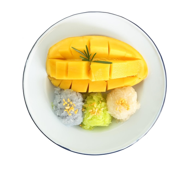 Фото Знаменитый тайский десерт вид сверху на сладкое свежее спелое манго с тремя цветами липкого риса, зеленым от пандана и фиолетовым от цветка гороха бабочки, выделенного на белом