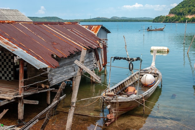 Thai fishing long boat next to the old rusty fisherman hut