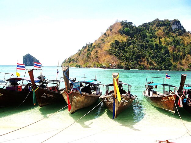 Foto bandiere thailandesi su barche ormeggiate sulla spiaggia