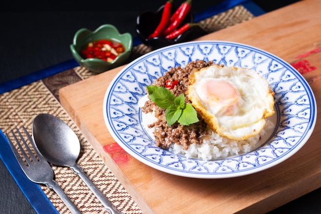 Photo thai food concept khao pad krapow rice and minced beef thai holy basil stirfry with fried egg in thai style ceramic plate with copy space