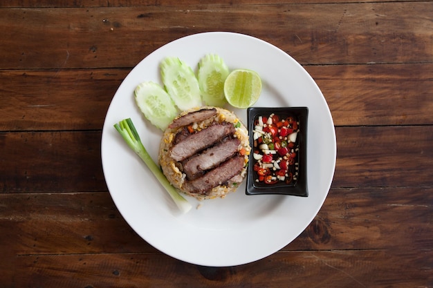 Thai food Grilled Pork Neck with fried rice and spicy sauce on wooden table top view.