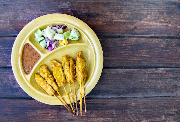 L'alimento tailandese di carne di maiale satay, carne di maiale arrostita è servito con salsa dell'arachide su vecchio fondo di legno.