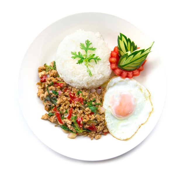 Thai food stir-fried pork spicy and basil served with rice and fried egg and tomato cucumber 