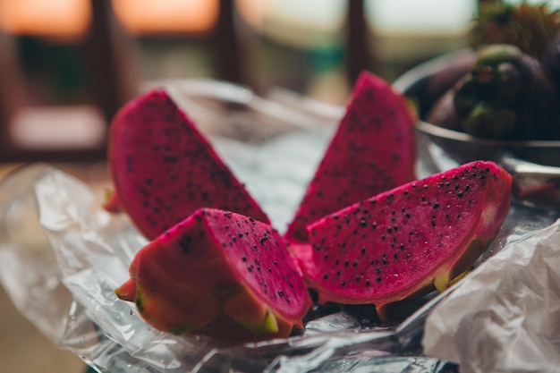 Thai fruit: dragon eye. Pink food cut into pieces on a plate close-up