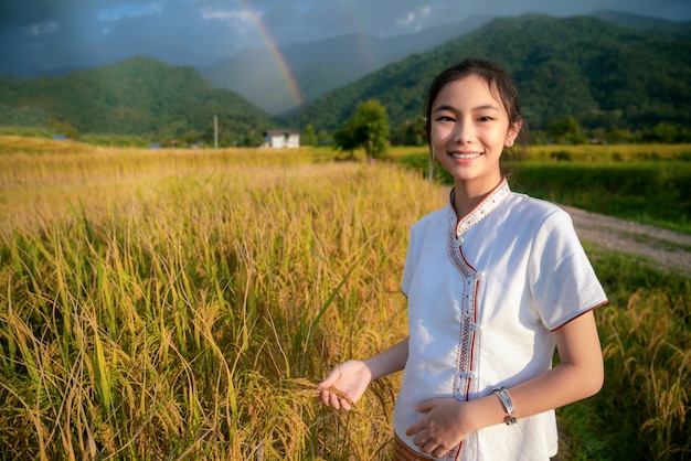 Thai girl walk on paddy and rice farm in lamduan woven cloth coffee shop