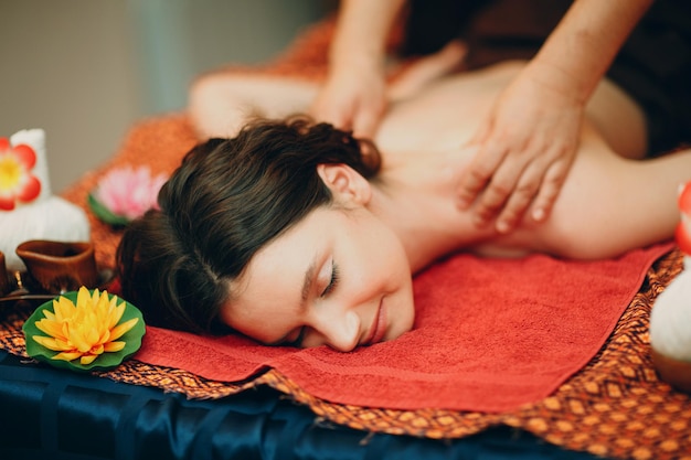 Thai man making classical thai massage procedure to young woman at beauty spa