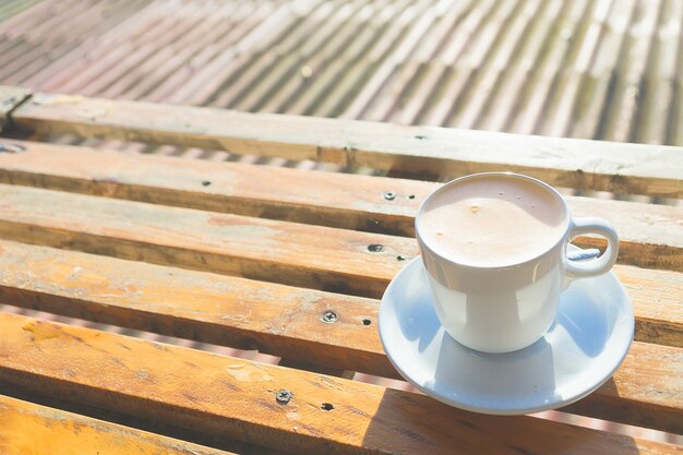 Thai milk tea in white ceramic cup put on the wooden table