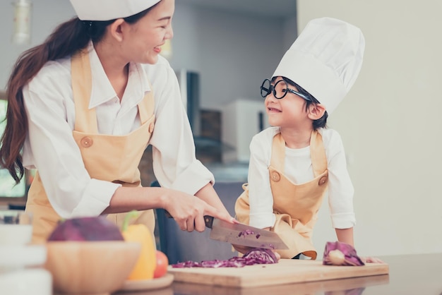 タイのお母さんと子供が家で一緒に料理をしています。社会的距離と外出禁止令安全を確保してください。家族の活動Covid-19の効果と発生ウイルスの阻止。自宅でロックダウンして自己検疫します。