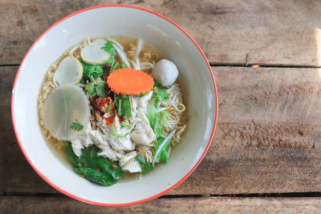 Photo thai noodle soup with chicken and fish ball and vegetable in a bowl