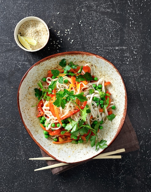 Thai noodles with vegetables on dark background top view