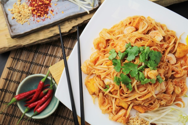 Thai pad with shrimps on a white plate, top view, chopsticks