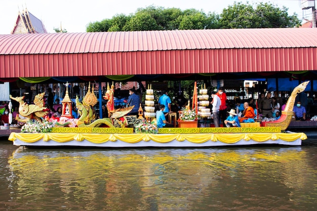 Thai people foreign traveler travel visit and join tradition merit ritual and praying offering alms giving to monk procession on boat in canal at Wat Sai Yai on November 8 2022 in Nonthaburi Thailand