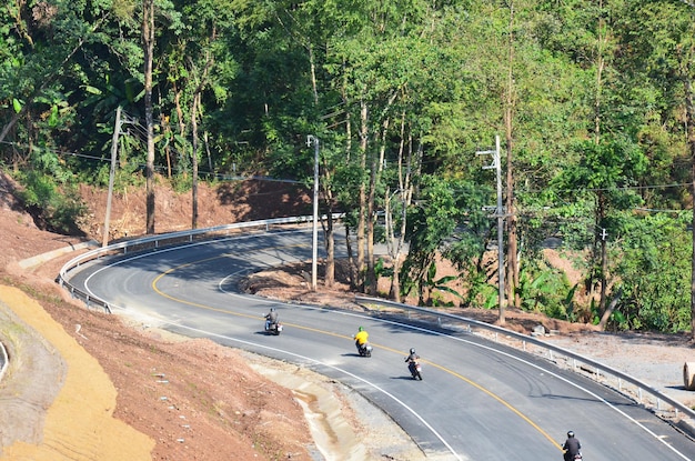 スリナン国立公園の道路でバイクに乗っているタイの人々と外国人旅行者は、ナンタイのボクルア地区のバンボクルア村に行きます