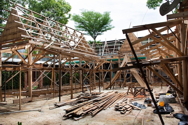 Thai professional carpenter people working and use teak build\
structure woodwork new building wooden church pavilion in\
construction site at wat sangkhatan temple in bang pai of\
nonthaburi thailand