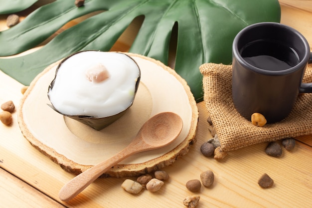 Thai Pudding Coconut top with taro, Desserts wrapped in banana leaves.Thai people call "Khanom Tako".Tako with Taro placed on a wooden saucer and wooden spoon, Top view.