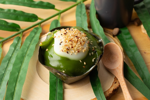 Thai Pudding Coconut with Fresh Pandanus top with sesame, Desserts wrapped in banana leaves.Thai people call "Khanom Tako".Tako placed on a wooden saucer and wooden spoon.